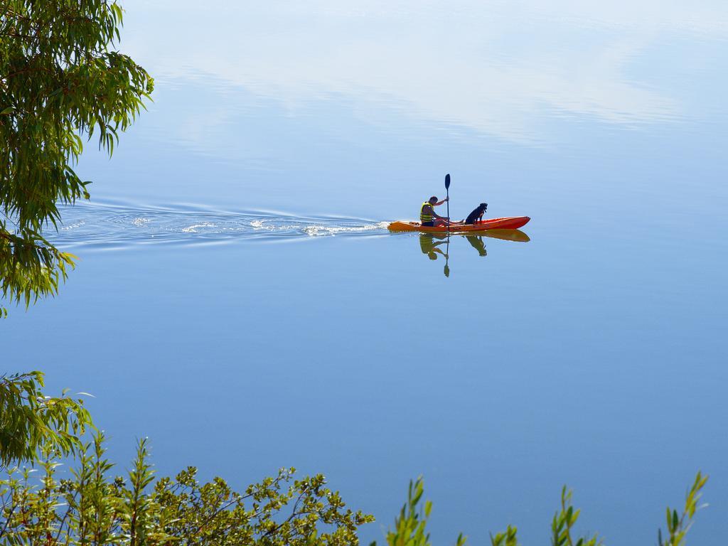 Ap Lago Montargil - Conference & Spa Eksteriør billede The photo shows a serene scene of a person kayaking on a calm body of water. The surface of the water is very smooth, reflecting the surroundings, and there is a gentle wake behind the kayak indicating movement. The kayaker is wearing a life jacket a