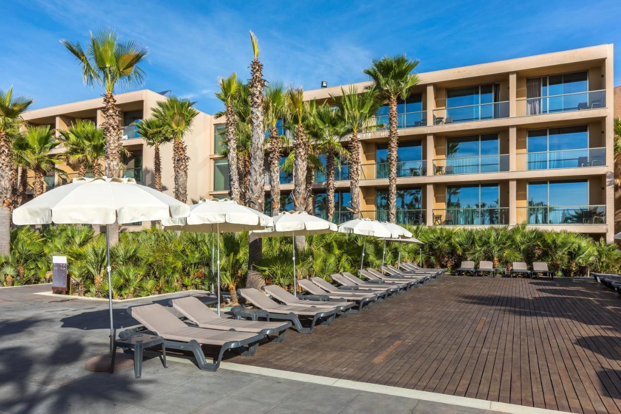 Ap Lago Montargil - Conference & Spa Eksteriør billede The photo shows a modern resort or hotel area featuring several lounge chairs lined up on a wooden deck. Each lounge chair is paired with a white umbrella, providing shade. In the background, there are palm trees, which add to the tropical atmosphere