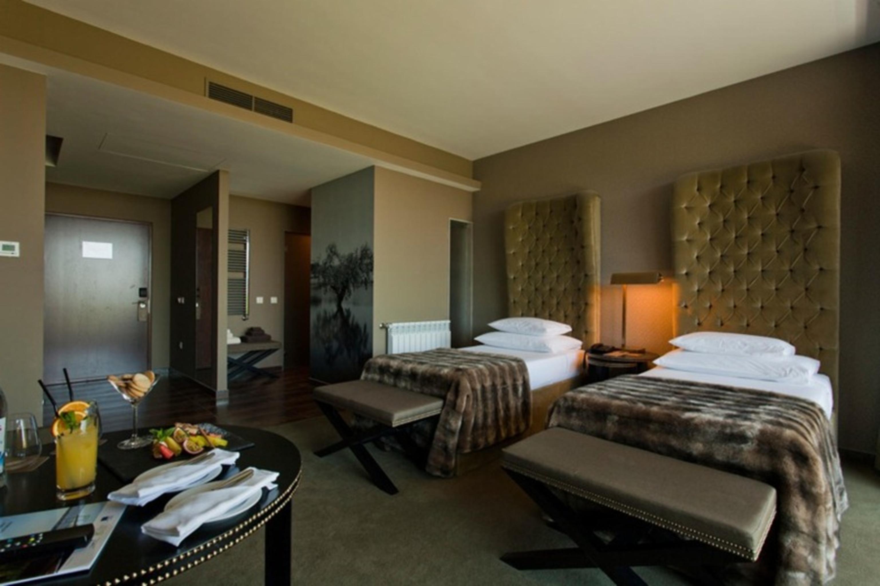 Ap Lago Montargil - Conference & Spa Eksteriør billede The photo shows a stylish hotel room featuring two beds with plush, upholstered headboards. The room has a modern and elegant design, with earthy tones dominating the decor. A small round table is set up in the foreground, displaying a drink and some