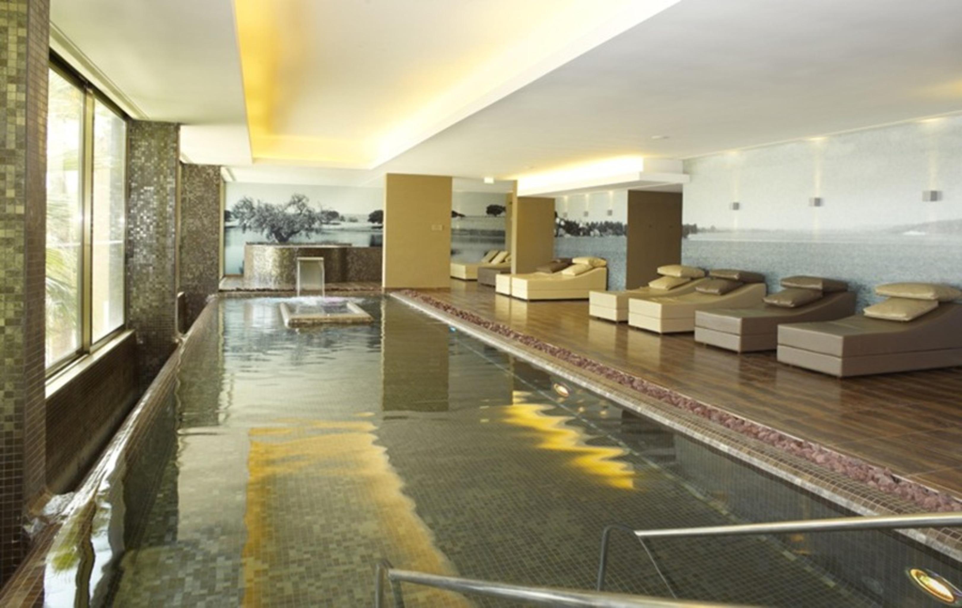 Ap Lago Montargil - Conference & Spa Eksteriør billede The photo shows a modern, serene spa environment. There is a swimming pool with calm water, reflecting the surrounding decor. Along the sides, there are several comfortable lounge chairs arranged, perfect for relaxation. Large windows allow natural l